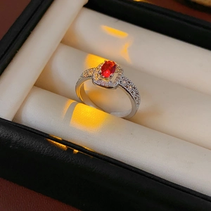 Macro shot of a silver ring with an oval red gemstone and square diamond halo