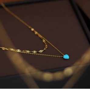 Macro shot of double-layered gold necklace featuring a blue opal heart-shaped pendant