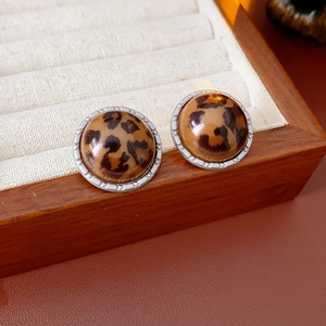 Détail macro de boucles d'oreilles léopard avec bordure argentée sur plateau à bijoux