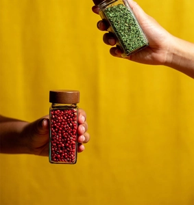 Close-up of square glass spice jars with acacia wood lids filled with herbs and pepper