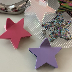 Macro shot of colorful star-shaped hair claws in pink, purple, and glitter acrylic finishes
