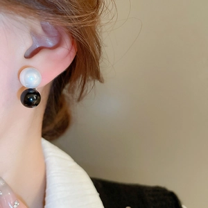 Detailed close-up of geometric black and white double ball faux pearl stud earrings