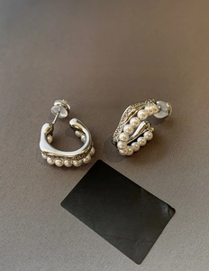 Detailed close-up of C-shaped silver earrings with white pearls and micro-pave rhinestones