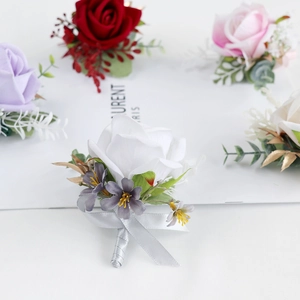 Elegant artificial rose boutonniere set with greenery and ribbons for wedding ceremony