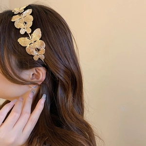 Close-up of golden butterfly headband featuring intricate layered metal wings on the side