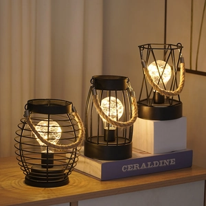 Detail of industrial iron wire lamps with hemp rope handles and warm glowing bulbs