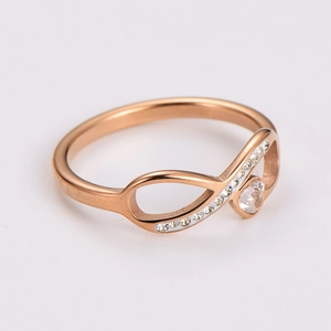 Detail of rose gold infinity ring with white crystals and heart stone on white background