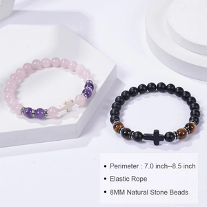 Détail de bracelets en perles de quartz rose et onyx de 8 mm avec croix sur socle blanc