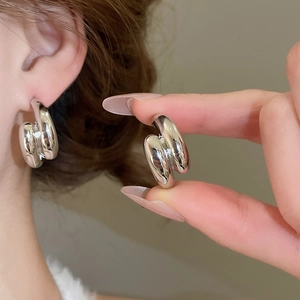 Detail showing chunky silver double layer drop cross C-shape earrings on model