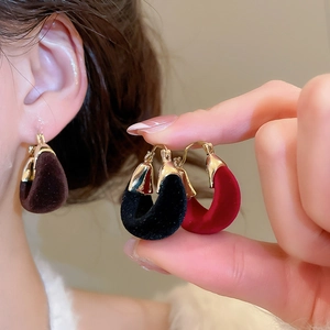 Detail of C-shaped flocked earrings in chocolate, black, and wine red velvet finish