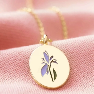 Vintage gold necklace with purple iris flower pendant on pink knit fabric texture