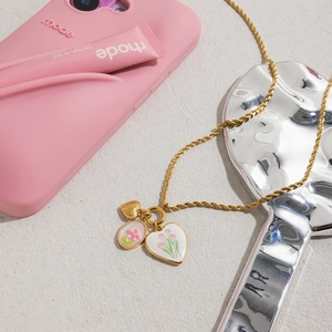 Détail du collier en acier doré avec pendentifs cœur et fleurs roses en émail chic
