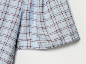 Detail of light blue plaid dress showing high-quality fabric texture and neat stitching
