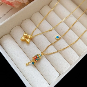 Detailed shot of golden flower pendant with zircon and enamel prayer wheel necklace