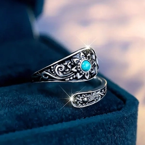 Macro view of vintage silver floral ring with a turquoise stone on blue velvet