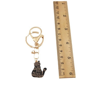 Golden cat keychain with black musical note pendant and Meowsic engraving on white background