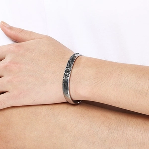 Close-up of vintage floral engraved silver cuff bracelet with intricate ethnic pattern detail