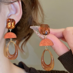 Detail showing amber resin and wood drop earrings with warm earthy tones for women