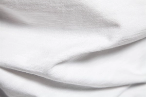 Macro shot of white cotton blend fabric texture with fine knit pattern and soft folds