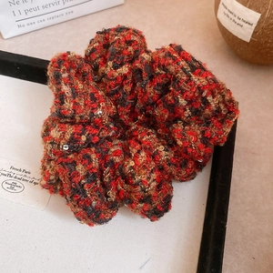 Texture détaillée du chouchou en tweed rouge et noir avec de fines paillettes argentées