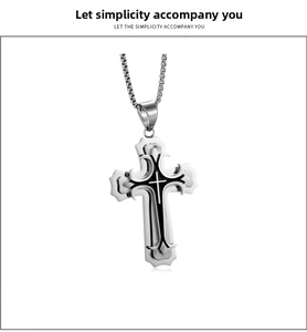Vue macro d'un pendentif croix en acier inoxydable à trois couches noires et argentées