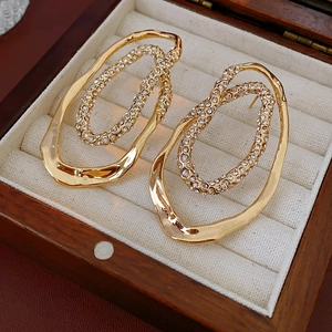 Detailed close-up of gold plated oval double hoop earrings with pavé rhinestones in a box