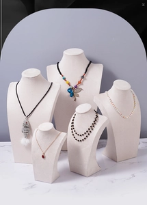 Detail showing various necklaces on velvet bust displays with marble background
