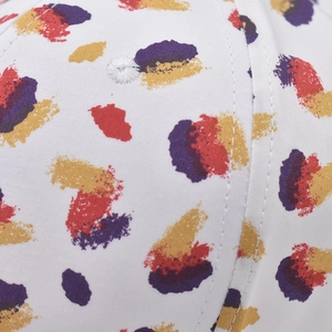 Detailed close-up of white twill cotton baseball cap with colorful brush stroke patterns