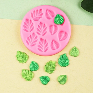 Maple and ginkgo leaf silicone mold with green fondant leaves on two-tone background