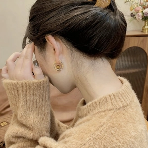 Close-up of vintage gold braided hoop earrings with brown tiger eye stone on model