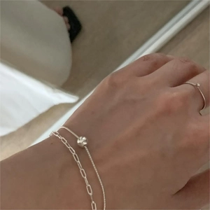 Detail of silver double-layered bead bracelet and minimalist thin band ring set