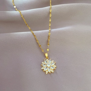 Macro detail of gold flower pendant with sparkling crystals on twisted chain necklace