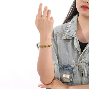 Close-up of a gold multi-link stainless steel watch chain bracelet on a model's wrist