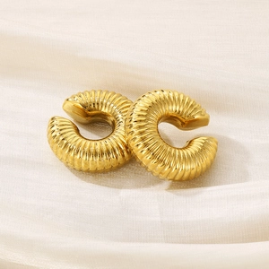 Detailed view of golden croissant hoop earrings with spiral texture on satin fabric
