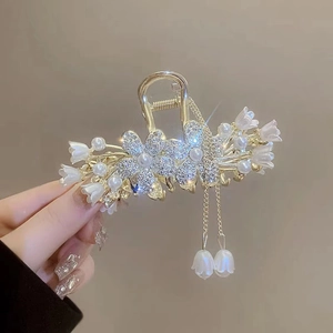 Detail van gouden haarklem met lelietjes-van-dalen bloemen en lange kwastjes