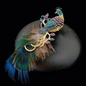 Elegant gold peacock feather brooch with colorful crystals on a black stone base