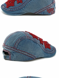 Detail of blue denim cap featuring red star embroidery and adjustable metal buckle