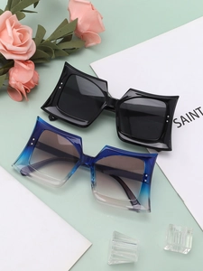 Close-up of oversized square sunglasses with pointed frames and decorative silver dots