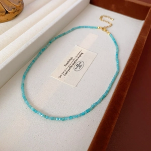 Détail d'un collier de perles bleues avec fermoir doré posé dans un coffret à bijoux blanc