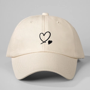 Close-up of heart embroidery on a cream cotton baseball cap with fabric texture details