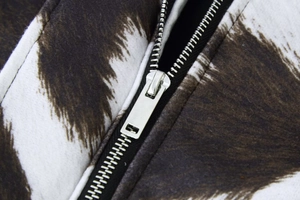 Close-up of a silver metal zipper on a stylish animal print cropped jacket fabric