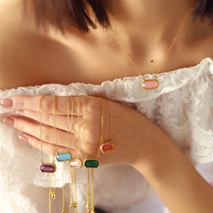 Gold chain necklace with a rectangular colorful zircon pendant on an elegant woman