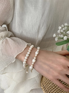 Detail of natural freshwater pearl bracelets with gold-plated beads on fabric background