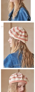 Detail showing the red and off-white striped knit texture of the beret on a model