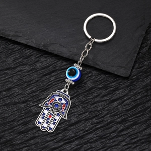 Vintage Hamsa Hand and Evil Eye alloy keychain pendant on a black stone surface