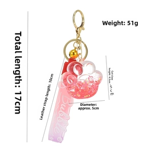 Detail of pink cat paw liquid keychain showing gold bell and purple leather strap