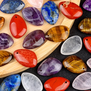 Polished teardrop natural stone pendants in amethyst and tiger eye on wooden tray