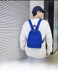 Rückansicht eines Models mit königsblauem Canvas-Rucksack in modernem Interieur
