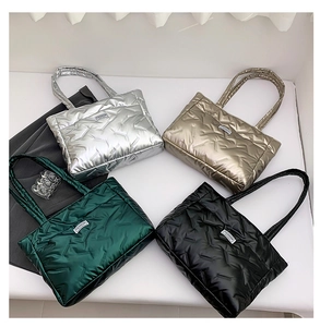 Flat lay of metallic quilted tote bags in silver, gold, green, and black with fashion tags