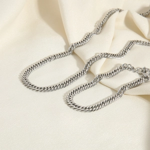 Detailed view of silver stainless steel 6mm Cuban link necklace on white silk fabric